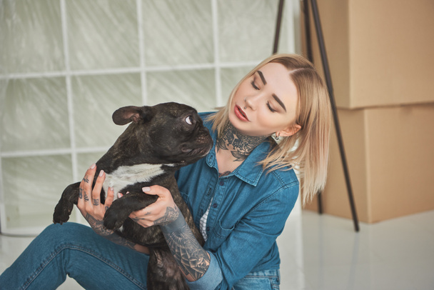 hermosa chica tatuada jugando con bulldog francés en un nuevo hogar
 - Foto, Imagen