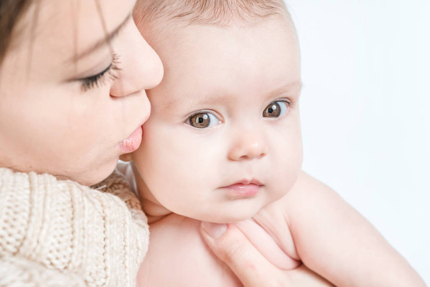 Mother kissing crying baby on a white background - Photo, Image