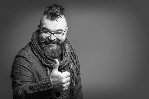 Smiling bearded man with a mohawk hairstyle showing thumb up. Toned - Photo, image