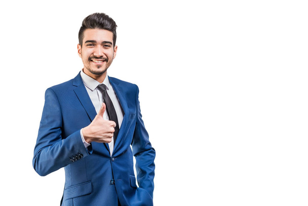 Young attractive man in a blue suit showing thumb up on a white background. Isolated - Φωτογραφία, εικόνα