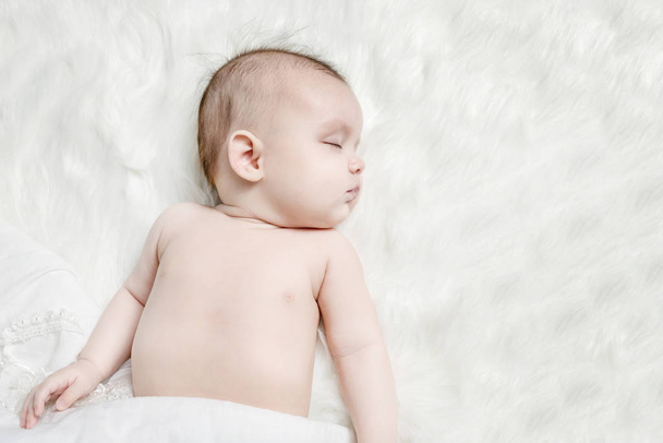 Cute baby sleeping on a white fluffy background - Valokuva, kuva
