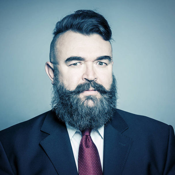 Adult bearded man in a suit on a blue background. Toned - Foto, immagini