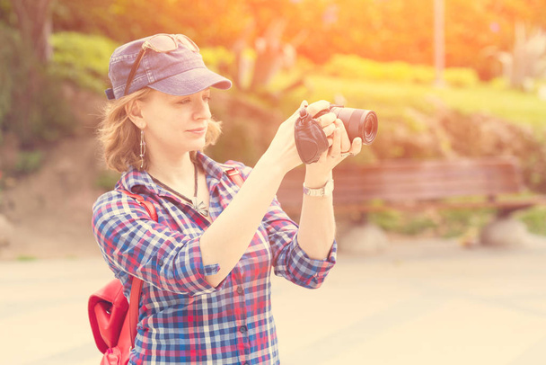 Woman in a red cap with a backpack looking into the camera in the sunlight - Foto, imagen