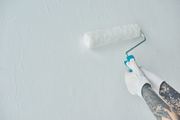 Kırpılan atış ile rulo boya fırça boyama duvar yeni evde dövmeli kadın - Fotoğraf, Görsel