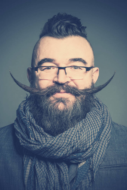 Adult bearded man in a scarf and glasses with long mustache. Toned - Photo, Image