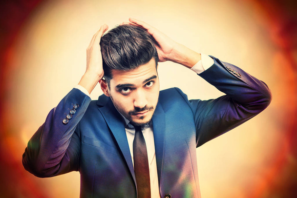 Young attractive man in a blue suit with hands near the head. Toned - Fotoğraf, Görsel