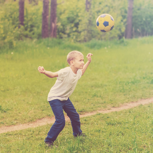 Blond boy playing with a ball in the park. Toned - Photo, image