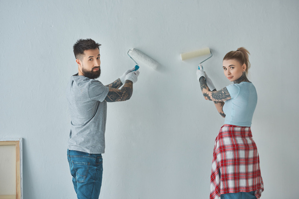 back view of young couple painting wall together at new apartment - Photo, Image