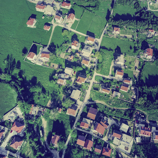 Yeşil çimenlerin üzerinde kırmızı kiremitli çatılı köy üstten görünüm ev sahipliği yapmaktadır. Tonda - Fotoğraf, Görsel