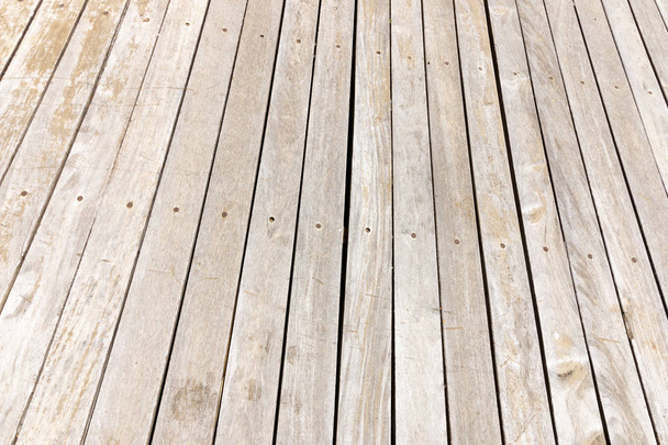 Μια κοντινή όψη του ξύλινο πάτωμα πλάκες που έχουν έχει αποχρωματιστεί από έξω ο σκληρός ήλιος  - Φωτογραφία, εικόνα