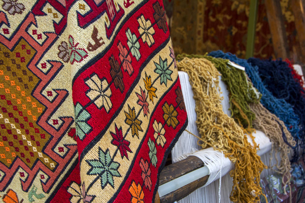 farbenfrohe traditionelle armenische Teppiche mit unterschiedlich farbigen dicken Wollfasern zur Herstellung von Teppichen auf der Webmaschine für Teppich als Hintergrund - Foto, Bild