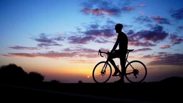 Polkupyöräilijän siluetti kalliolla auringonlaskun aikaan
 - Materiaali, video