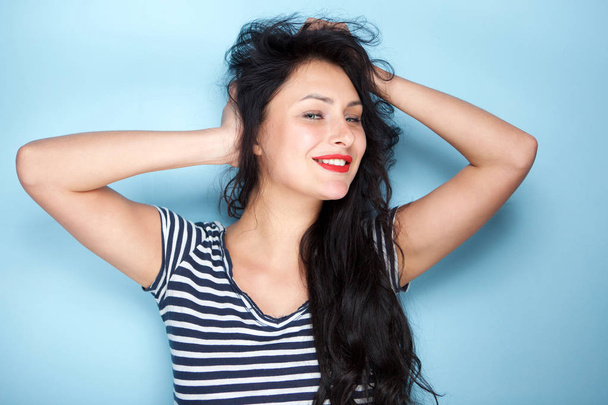 Portrait of carefree young woman smiling with hands in hair - Photo, Image