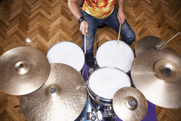 молодой перкуссионист репетирует на барабанах в репетиционной студии, вид с воздуха
 - Фото, изображение