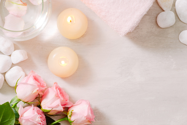 Rose flower, essential oil, wooden tray with clean towels and lighting candles in spa - Photo, Image