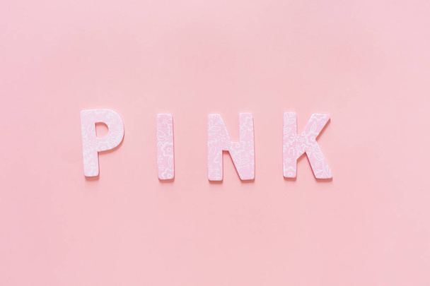 PINK palabra hecha de letra pequeña de madera rosa sobre fondo rosa, plano
 - Foto, imagen
