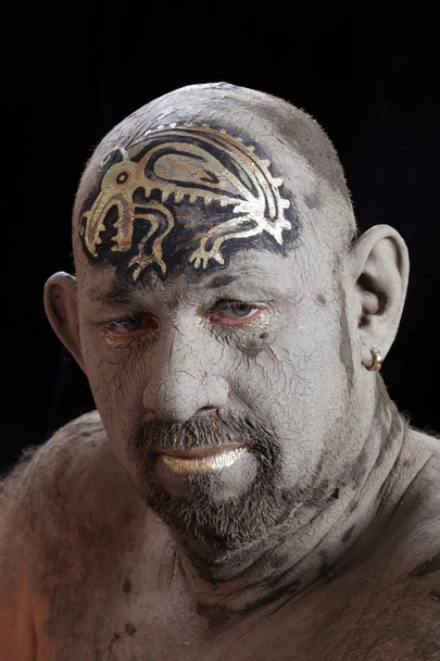 close-up portrait of a man in the clay body art , studio on a dark background - Фото, изображение