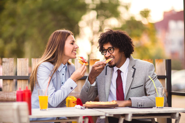 Feliz equipo de negocios jóvenes comiendo pizza en la cafetería al aire libre.Concepto de negocios, comida y gente
. - Foto, imagen