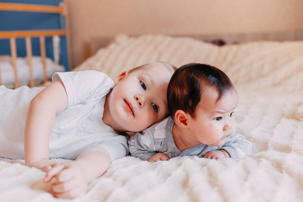 Petite fille mignonne de quatre mois et son frère aîné, jouant sous la couette à la maison dans le lit dans la chambre, souriant joyeusement
 - Photo, image