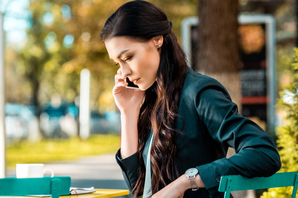 attrayant femme d'affaires parlant par smartphone au café de rue et regardant vers le bas
 - Photo, image