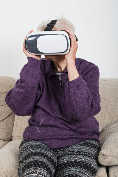 Elderly retired woman experiencing virtual reality video with headset - Фото, зображення