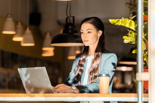 attrayant brunette pigiste travaillant avec ordinateur portable au café
 - Photo, image