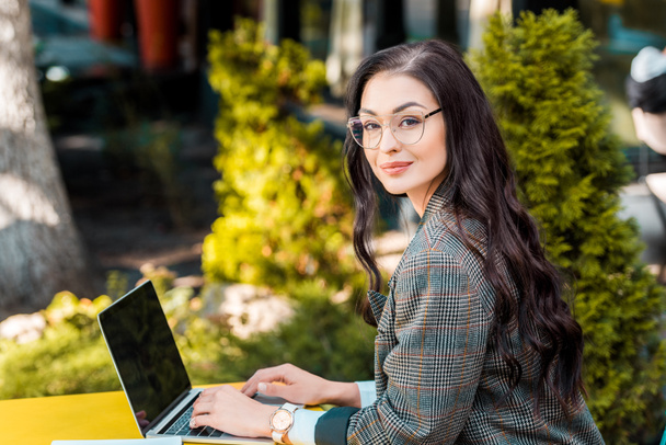 attractive brunette businesswoman teleworking with laptop at restaurant terrace - Foto, afbeelding