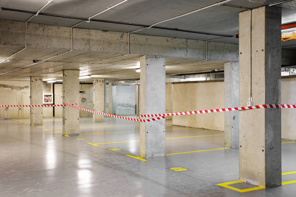 Estacionamento subterrâneo renovado com marcação de lote amarelo, numeração e fita de aviso
 - Foto, Imagem