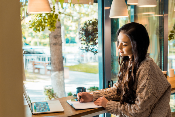 mooie freelancer werken met planner en laptop in de coffeeshop  - Foto, afbeelding