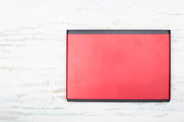 Red laptop computer isolated on white wooden background, top view with copy space - Fotografie, Obrázek