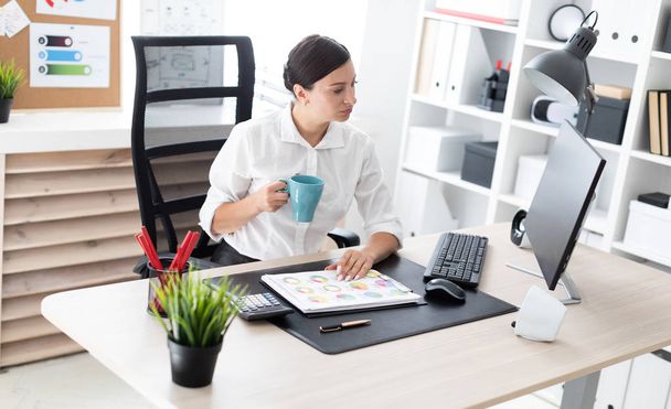  Beautiful young businesswoman with coffee working in a bright office.She has dark hair. Shes wearing a white shirt.  - Photo, image