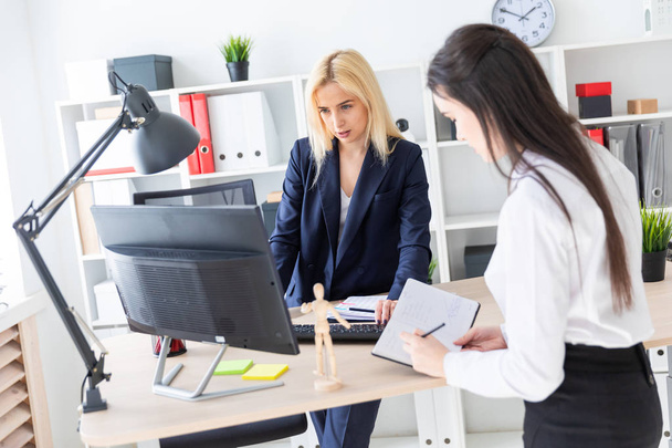 Two girls stand in the office near the table and work with documents. - 写真・画像