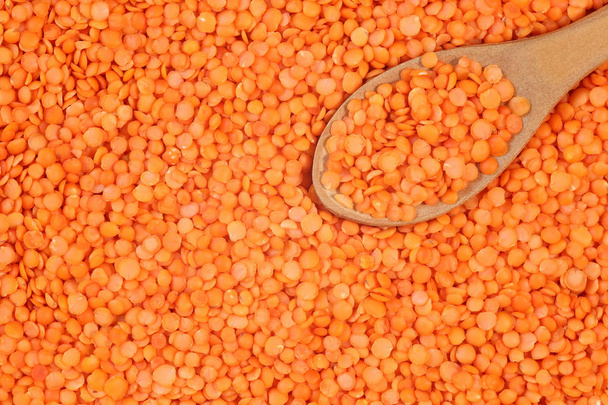 Close up of raw, dehulled red lentil background with wooden spoon - Photo, Image