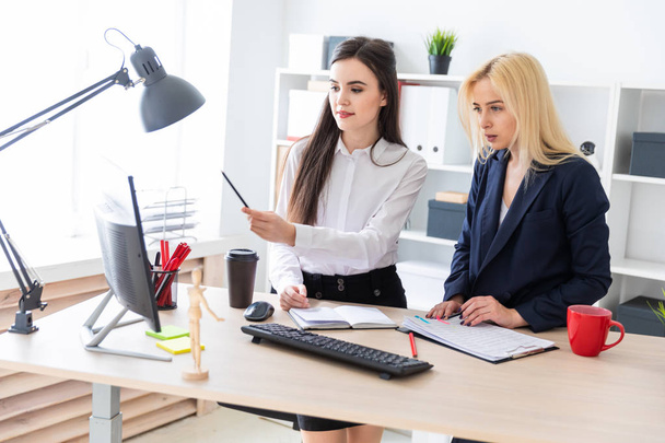 Two girls stand in the office near the table and work with documents. - Photo, Image
