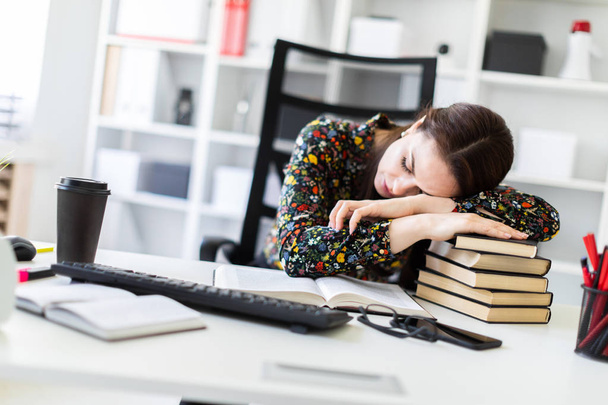 tired economist sleeping while leaning on stack of books at workplace in office   - Foto, imagen