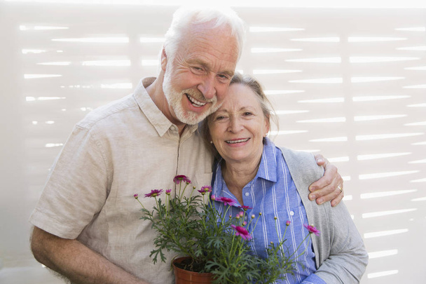 Портрет счастливой активной пожилой пары с цветочными горшками
 - Фото, изображение