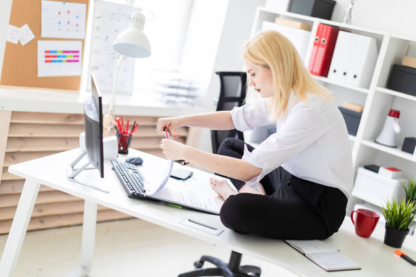 jovem empresária sentada em uma mesa no escritório e trabalhando com documentos e computador
. - Foto, Imagem