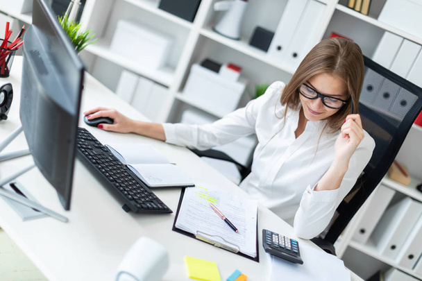 Молодая девушка сидит за столом и работает в офисе
 - Фото, изображение