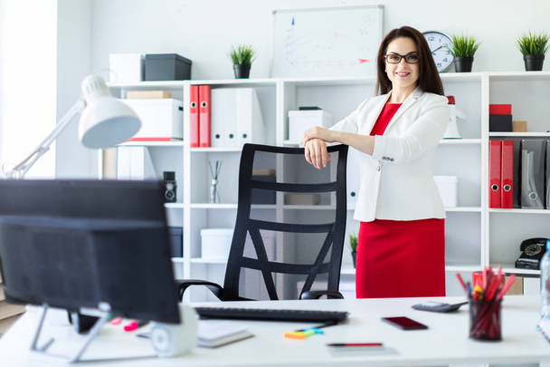 Beautiful young girl in a business suit is standing in the office near table - Photo, Image