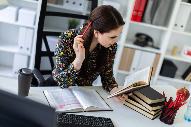 економіст з ручкою в руці уважно читає бізнес-книгу і сидить за столом у яскравому офісі
  - Фото, зображення