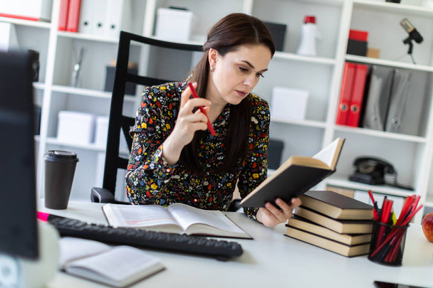 économiste avec stylo à la main lisant attentivement le livre d'affaires et assis à table dans un bureau lumineux
  - Photo, image