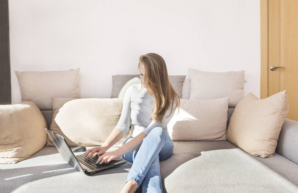 white girl with long hair in jeans sitting on the couch with a laptop,  man and gadget - Foto, immagini
