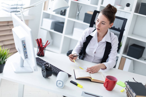 Ein schönes junges Mädchen mit einem Strauß auf dem Kopf, weißem Hemd und schwarzer Weste arbeitet in einem hellen Büro. Foto mit Schärfentiefe - Foto, Bild