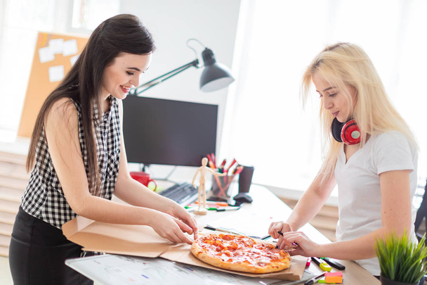 オフィスでピザを食べる 2 人の女の子. - 写真・画像
