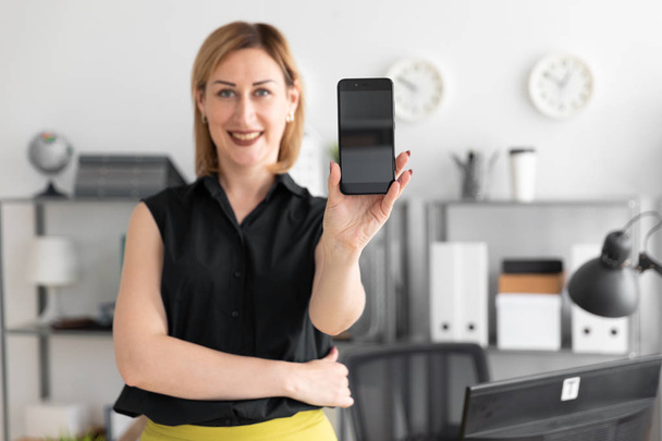 young businesswoman standing in the office and shows the phone screen - Photo, Image