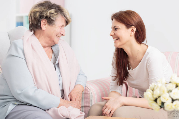 Smiling elderly woman during meeting with friendly nurse during meeting at home - Foto, imagen