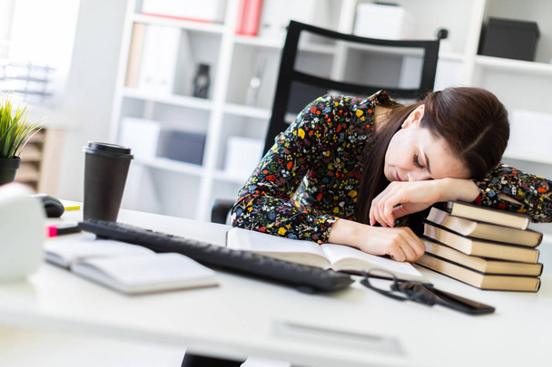 economista cansado durmiendo mientras se apoya en la pila de libros en el lugar de trabajo en la oficina
   - Foto, Imagen