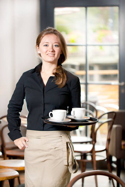 Portrait of waitress holding tray of coffee cups in cafe - Фото, зображення