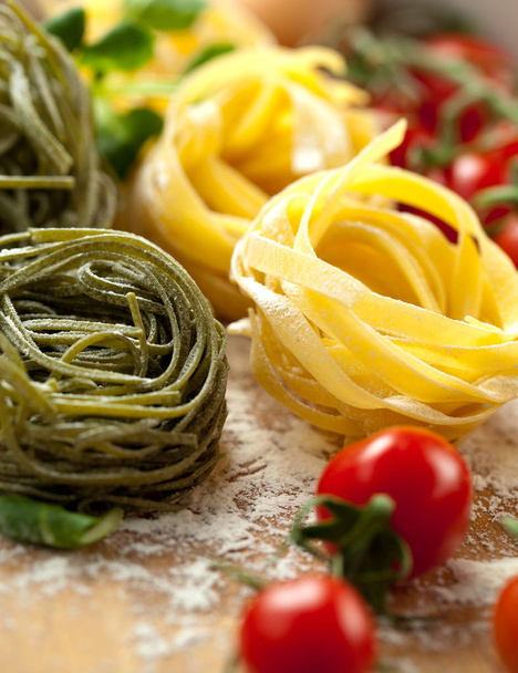 Tagliatelle pasta with fresh basil and tomatoes on rustic table - Foto, afbeelding