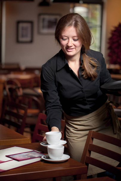 Portrait of waitress holding tray of coffee cups in cafe - Fotografie, Obrázek